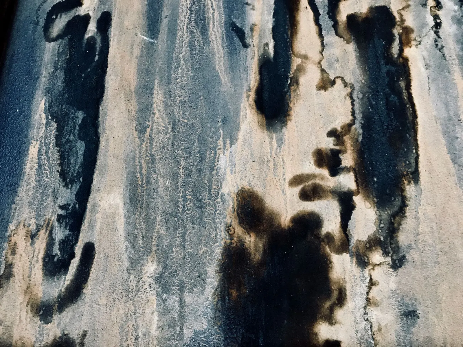 Dark mildew staining and water tracks running down a weathered light-coloured wall surface