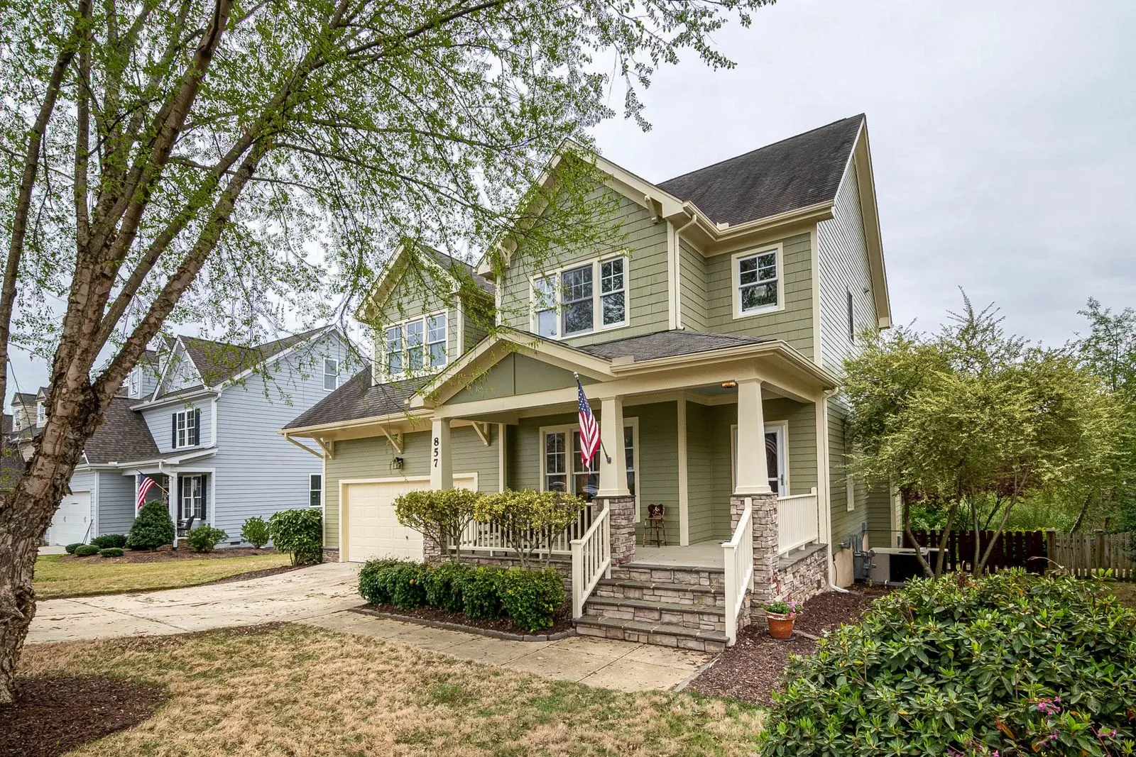 Suburban house with a covered front porch, garden beds and a driveway on a clear day